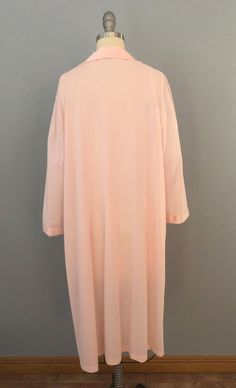 "Vintage robe from the 60's era!! Super soft, silky nylon in a pink-peachy color. Gorgeous appliqued floral embroidery. Collared open v-neck with buttondown front and fabric-covered buttons. Long bell sleeves. One hip pocket. Ankle length. Curl up, and just relax in this sweet robe! Fits a large frame but please double-check the measurements below to ensure the best fit for you. -- M E A S U R E M E N T S --- Bust: 46\" Waist: 48\" HIps: 50\" Shoulders: 17.5\" Length: 43\" Fabric: Dacron polyest Pink Robe For Spring Sleepwear, Pink Feminine Robe For Sleepover, Pink Robe For Sleep And Spring Season, Feminine Pink Robe For Sleepover, Pink Spring Robe For Loungewear, Long Sleeve Pink Nightgown For Spring, Oversized Long Robe For Daywear, Pink Long Robe For Spring, Long Pink Robe For Spring