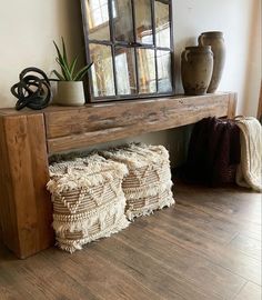 a wooden bench sitting on top of a hard wood floor next to a vase and mirror