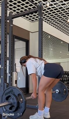 a woman is squatting down in front of a barbell exercise machine at the gym