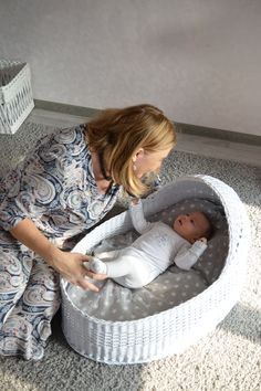 a woman sitting on the floor with a baby in her lap and looking at it