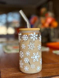 a glass jar with a straw in it sitting on a wooden table next to plates and utensils