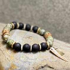 The green beaded bracelet is an authentic piece of Native American jewelry, inspired by nature and crafted in a bohemian style. This spiritual protection bracelet is perfect for men seeking a meaningful and culturally significant accessory. 🪶 𝗠𝗔𝗧𝗘𝗥𝗜𝗔𝗟𝗦 + 𝗗𝗜𝗠𝗘𝗡𝗦𝗜𝗢𝗡𝗦 ❯  10mm Rhyolite, Jasper, Wood, Abalone Shell, Brass ❯  Heavy Duty Elastic Cording 🪶 𝗦𝗧𝗢𝗡𝗘 + 𝗘𝗟𝗘𝗠𝗘𝗡𝗧 𝗘𝗡𝗘𝗥𝗚𝗬 ❯  NUMEROLOGY POWER OF 1 signifying courage, focus, will, and enlightenment ❯  RHYOLITE Handmade Bohemian Stretch Bracelet For Meditation, Bohemian Bracelets For Meditation, Bohemian Gemstone Beads Bracelets For Beach, Earthy Natural Stone Beaded Bracelets For Beach, Bohemian Gemstone Beads Bracelet For Beach, Earthy Green Bracelets For Meditation, Nature-inspired Beaded Bracelets For Healing, Bohemian Green Stretch Bracelet With 8mm Beads, Green Bohemian Stretch Bracelet With 8mm Beads