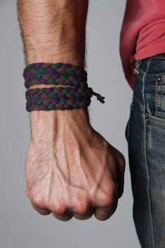 a man wearing a purple, green and black braided leather bracelet on his wrist