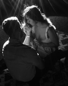 a man kneeling down next to a woman on top of a bed with sunbeams