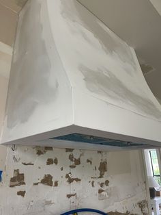 a white stove top oven sitting inside of a kitchen next to a wall with peeling paint on it