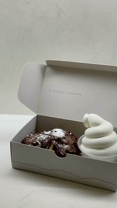 a cupcake with icing in a box on a white tableclothed surface