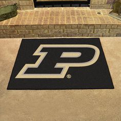 a black and white door mat with the letter p on it in front of a brick building