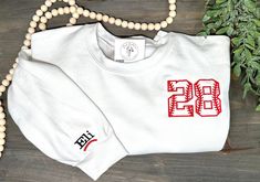 This embroidered custom baseball sweatshirt is perfect for game days! Show off your child's name and number with this custom design.  Please provide the name and number to be embroidered and verify the spelling prior to ordering as it will be stitched the way you enter it.  Please message me with any questions! -Sunni Game Day White Sweatshirt With Embroidered Graphics, Team Spirit Sweatshirt With Custom Embroidery For Game Day, White Game Day Sweatshirt With Embroidered Graphics, Sporty Sweatshirt With Custom Embroidery For Game Day, White Embroidered Logo Sweatshirt For Game Day, White Embroidered Logo Athletic Sweatshirt, White School Spirit Sweatshirt For Baseball Season, Customizable White Varsity Sweatshirt, White School Spirit Sweatshirt For Sports Season