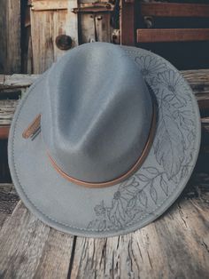 Add a touch of sophistication and style to your wardrobe with this stunning gray felt flat brim fedora hat. Handcrafted with care, this hat features a unique burned feather and floral motif, adding a touch of elegance to your look. The adjustable design ensures a comfortable fit for all head sizes, making it a versatile accessory for both men and women. The high-quality felt material provides durability and warmth, making it perfect for any season. Whether you're heading to a formal event or sim Gray Brimmed Fedora For Spring, Gray Short Brim Fedora For Spring, Flat Hats, Grey Flats, Felt Fedora, Hat Ideas, Felt Material, Fedora Hat, Hat Designs