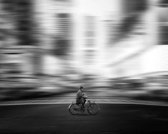 a man riding a bike down the middle of a street in front of tall buildings