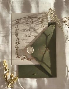 the wedding card is laying next to some flowers