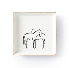 two horses on a white plate with gold trim around the edges and black ink drawing