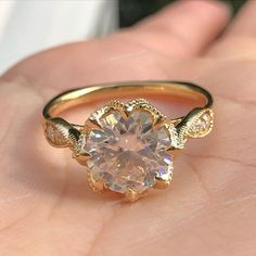 a close up of a person's hand holding a ring with a diamond in it