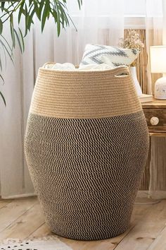 a large woven basket sitting on top of a wooden floor next to a lamp and table