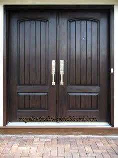 two brown double doors with metal handles on each side and brick walkway in front of them