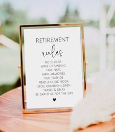 a sign that says retirement rules sitting on top of a wooden table next to a feather