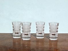 five glasses sitting on top of a wooden table next to each other with one empty glass in the middle