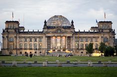 people are walking around in front of a large building with a dome on the top