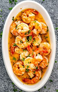 a white bowl filled with cooked shrimp and garnished with parsley on top