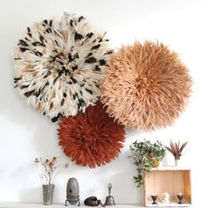 three different types of wall hangings on a white wall above a mantel with candles and vases