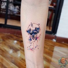 a small dog tattoo on the right leg, with watercolor splatters all over it