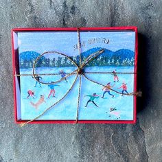 a christmas card is wrapped in twine and tied to a red box on the ground