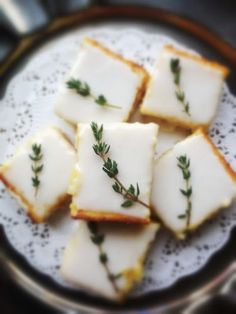 small pieces of food on a plate with some green sprigs in the middle