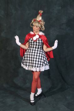 a woman in a dress and cape posing for the camera with her hands on her hips