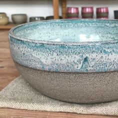 a blue and white bowl sitting on top of a wooden table next to a cloth