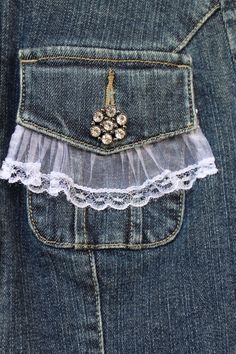 a pocket with some lace on it and two flowers in the pocket, attached to an old pair of jeans