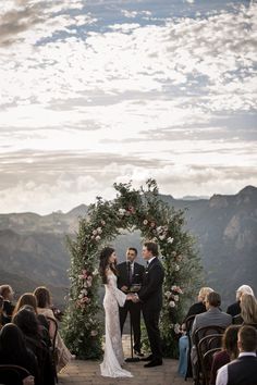 a bride and groom standing at the end of their wedding ceremony with mountains in the background