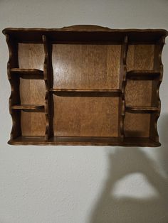 an old wooden shelf with several compartments on the top and bottom, hanging from a wall