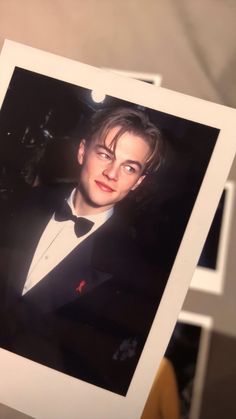 a man in a tuxedo and bow tie is holding up a polaroid