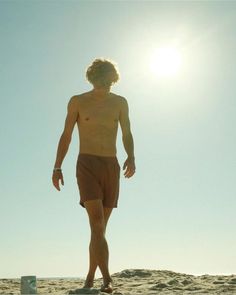 a man standing on top of a sandy beach next to a frisbee under a blue sky