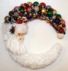 a christmas wreath made out of balls and other ornaments is hanging on the white wall