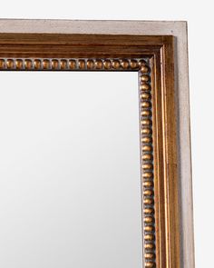 an ornate gold framed mirror with beading on the edges and sides, against a white background