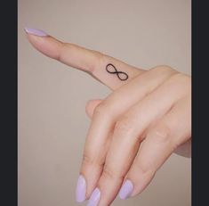 a woman's finger with an infinite sign tattoo on it