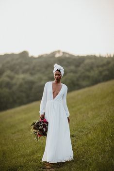 a woman in a white dress holding a bouquet and wearing a turban on her head