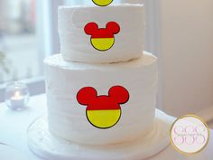 three tiered cake with mickey mouse faces on it's sides and yellow circles