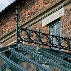 an old brick building with a glass roof and wrought iron railing