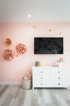 a flat screen tv mounted to the side of a pink wall in a living room