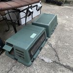 three green boxes sitting on the ground next to a table with chairs and other items