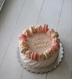 a birthday cake is decorated with macaroons and icing on a white table