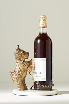 a bottle of wine sitting next to a bear figurine on a white surface