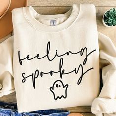 a white sweatshirt with the words feeling spooky on it next to some shoes