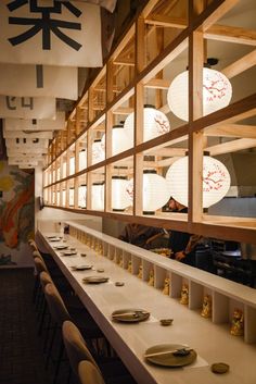 people are sitting at tables in a restaurant with lanterns hanging from the ceiling above them