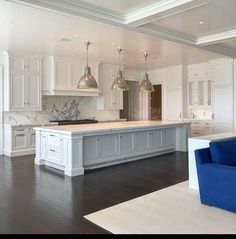 a large kitchen with white cabinets and blue couches in front of the countertop