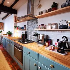 a kitchen with blue cabinets and wooden counter tops, pots on the shelves above the stove