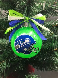 a football ornament hanging from a christmas tree with a seattle helmet on it