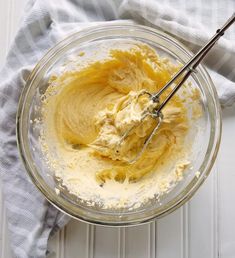 a glass bowl filled with batter on top of a white table next to a blue towel